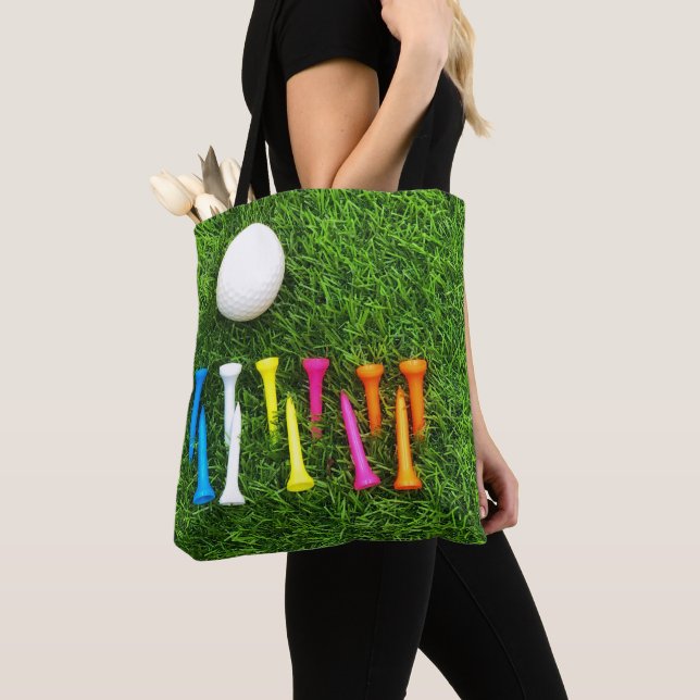 Golf tees are on green grass. tote bag (Close Up)