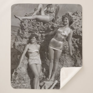 GRAYSCALE PHOTO OF THREE WOMEN STANDING AND SITTIN SHERPA BLANKET