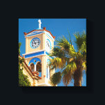 Greece - Orthodox Greek Church with Palm Tree Canvas Print<br><div class="desc">A bright and summery photograph taken in Greece. An orthodox greek church and its quaint clock tower and steeple. Vibrant colours on this structure are sandstone coloured brick with accents in santorini blue. A giant leafy palm tree hovers above. The sky is clear blue and shows off the stark white...</div>