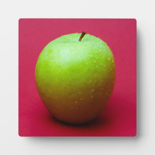 Green apple on red background plaque