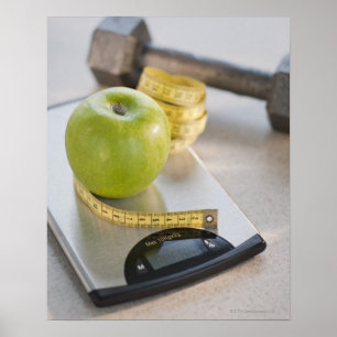 Green apple on weight scale, tape measure and poster