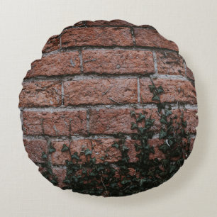 Green-leafed plants near brick wall round cushion