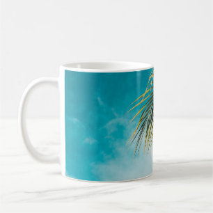 Green palm tree under blue sky coffee mug