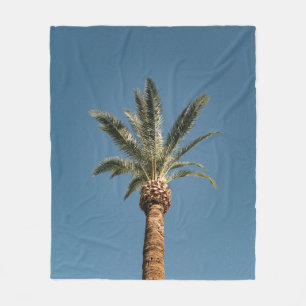 Green palm tree under blue sky in the morning fleece blanket