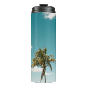 Green palm tree under blue sky in the morning thermal tumbler