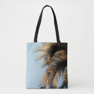 Green palm tree under blue sky in the morning tote bag