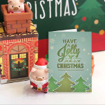 Green Paper Christmas Trees Holiday Card<br><div class="desc">Paper Christmas trees in shades of green,  outlined in white.  Snowflakes appear to be falling down a blue green textured background.  Green typography with holly.</div>