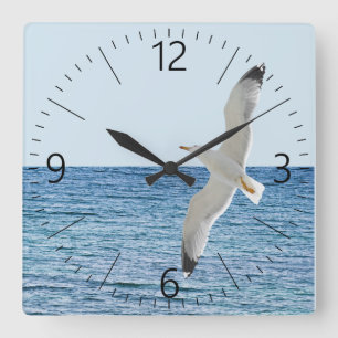 Gull flying above a sea square wall clock