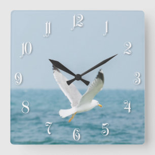 Gull flying above sea square wall clock