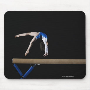 Gymnast (9-10) flipping on balance beam, side mouse mat
