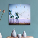 Hawaii Palm Tree Purple Landscape Photo Stylish Square Wall Clock<br><div class="desc">Appreciate the beauty of nature whenever you check the time on this blue and purple softly lit photography wall clock of palm trees blowing in the Hawaiian breeze against a mountain backdrop. Your choice of a round or square clock face. Makes a great housewarming gift! You can easily personalise this...</div>