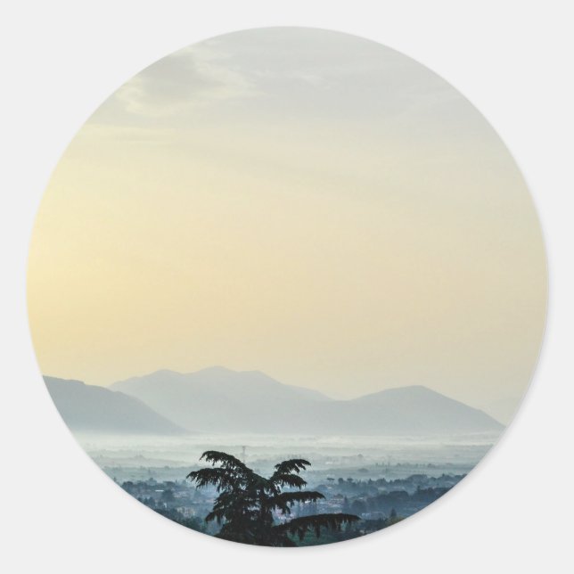 Hazy morning rooftops and a tall tree classic round sticker (Front)