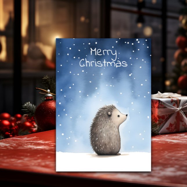 Hedgehog Christmas Holiday Card (A Christmas card with a cute illustration of a hedgehog is shown on a table with decorations around )