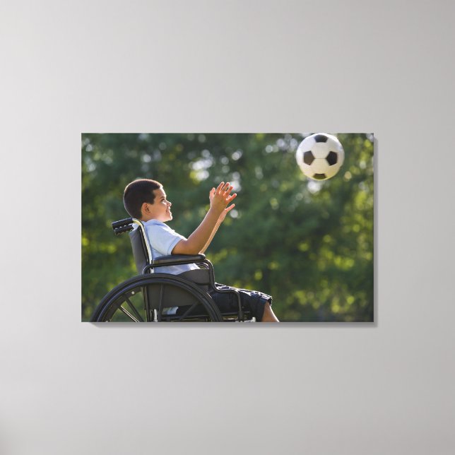Hispanic boy, 8, in wheelchair with soccer ball canvas print (Front)