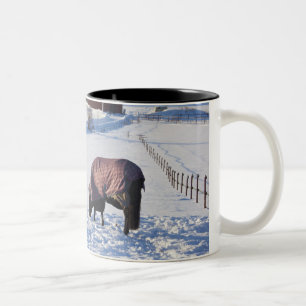 Horse grazing on a snow-covered field on Ekero 2 Two-Tone Coffee Mug