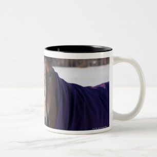Horse grazing on a snow-covered field on Ekero Two-Tone Coffee Mug