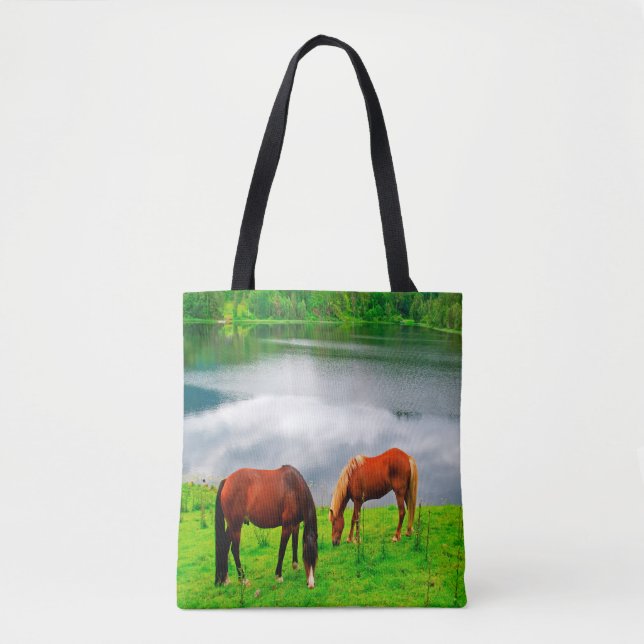 Horses grazing meadow with a forest lake tote bag (Front)