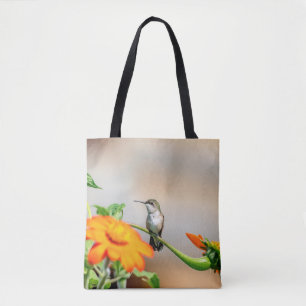 Hummingbird on a flowering plant tote bag