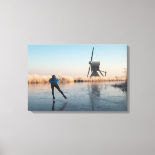 Ice skating past windmill and reeds canvas print