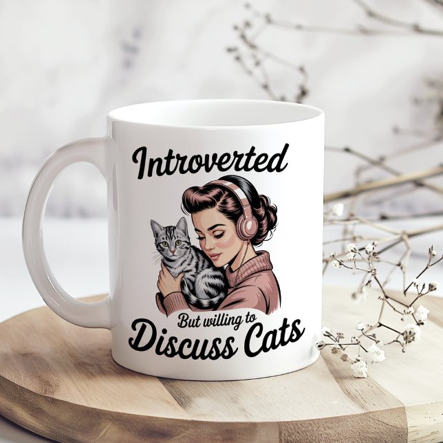 "Introverted But Willing to Discuss Cats" Funny Coffee Mug ("Introverted But Willing to Discuss Cats" Funny Coffee Mug on a sunny boho kitchen table.)