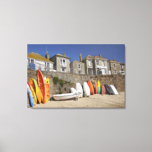 Kayaks and dinghies stacked against seawall at canvas print