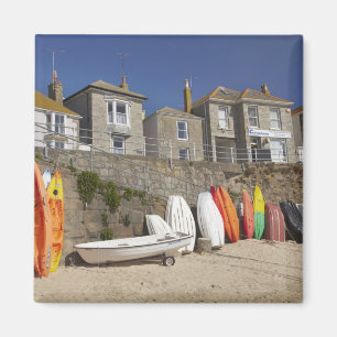Kayaks and dinghies stacked against seawall at magnet