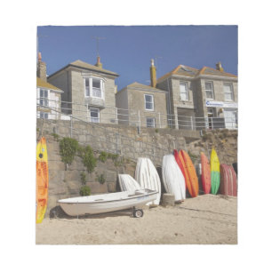 Kayaks and dinghies stacked against seawall at notepad
