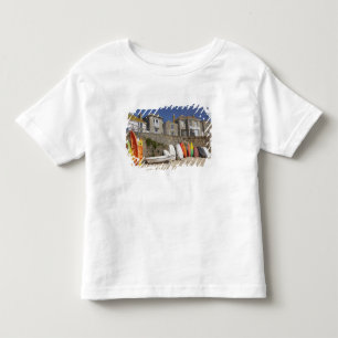 Kayaks and dinghies stacked against seawall at toddler T-Shirt