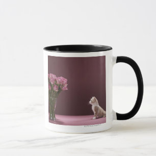 Kitten looking at vase of roses mug