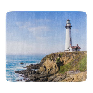 Lighthouse on hill blue sky white house ocean cutting board