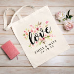 Love Pink Watercolor Flowers Wedding Monogram Tote Bag<br><div class="desc">Personalised tote bag design features the word "Love" in a black hand-lettered script typestyle, framed by a beautiful watercolor painted floral design of pastel pink, blush, and peach spring dahlia and rose flowers and green leaves. Also included is a monogram of the bride & groom names and wedding date that...</div>