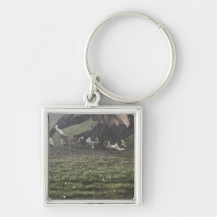 Lower section of rugby player in scrum, pushing key ring