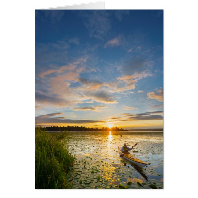 Male kayaker paddling sea kayak on still water (Front)
