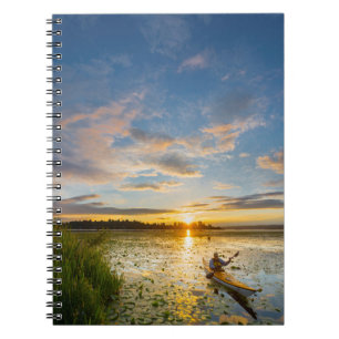 Male kayaker paddling sea kayak on still water notebook