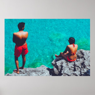 Man and woman sitting on boulder near body of wate poster