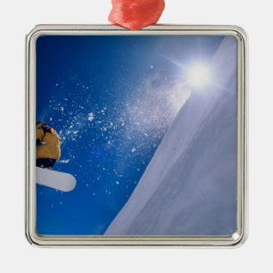 Man flying through the air on a snowboard with metal tree decoration
