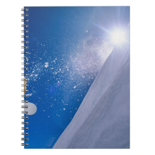 Man flying through the air on a snowboard with notebook