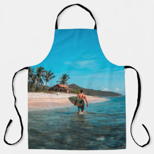 Man holding surf board in body of water apron