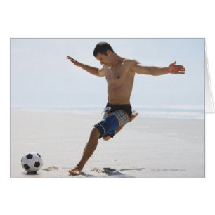 Man kicking soccer ball on beach