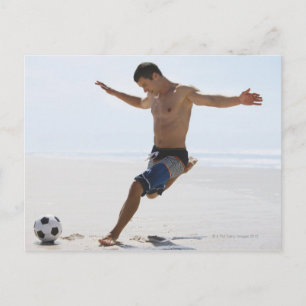 Man kicking soccer ball on beach postcard