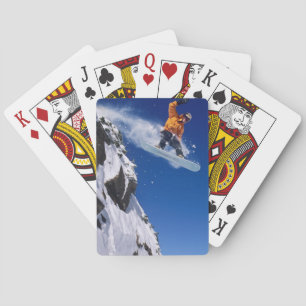 Man on a snowboard jumping off a cornice at playing cards