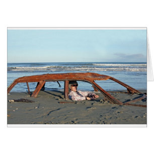 Man sitting in rusty car on beach