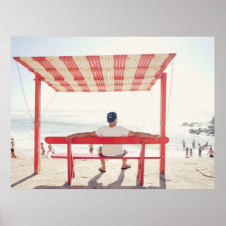 Man sitting on bench near beach poster