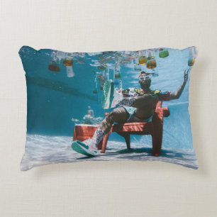 Man sitting on chair underwater with floating bott decorative cushion