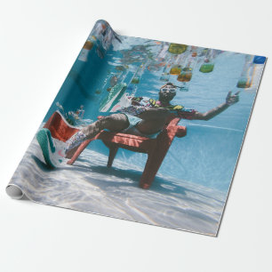 Man sitting on chair underwater with floating bott wrapping paper