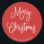 Merry Christmas | Handwritten Script on Red Classic Round Sticker<br><div class="desc">This simple and trendy holiday sticker says "Merry Christmas" in rustic,  white handwritten script on a bright,  holiday red background.</div>