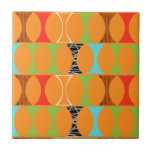 Mid Century Modern Orange Pattern Ceramic Tile<br><div class="desc">Knock, knock. Who's there? Mid Century Modern Orange Pattern Ceramic Tile! Hey, with a design this retro, you don't need a punch line. This perfectly mod pattern features a vibrant orange background and rows of an adorably kitschy shape in green, red, turquoise, black & white, and wood grain. The shape...</div>