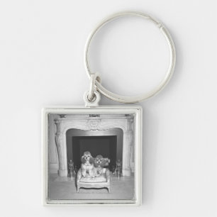 Miniature poodles sitting in front of fireplace key ring