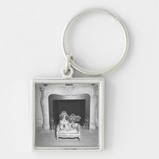 Miniature poodles sitting in front of fireplace key ring