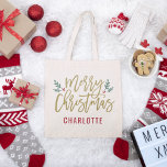 Modern Gold Script Merry Christmas Custom Name Tote Bag<br><div class="desc">Stylish Merry Christmas tote bag design features festive green branches of holly leaves and red berries accent the modern antique gold script design. The custom monogram text can be personalized a name or other text.</div>
